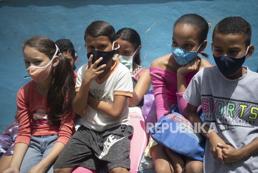 Program Pangan Dunia akan Pasok Makanan untuk Anak Venezuela.  Anak-anak yang mengenakan masker wajah sebagai tindakan pencegahan terhadap coronavirus baru menunggu di luar dapur umum untuk menerima makan siang paket-dan-pergi di lingkungan Petare di Caracas, Venezuela, Rabu, 15 Juli 2020, di tengah pandemi coronavirus baru.