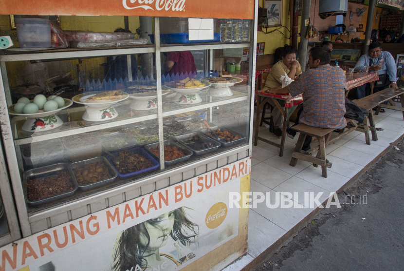 Sejumlah warga menyantap sajian yang dijual salah satu warung makan di Kemayoran, Jakarta, Senin (26/7/2021). Pemerintah menyesuaikan aturan Pemberlakuan Pembatasan Kegiatan Masyarakat (PPKM) level 4 pada pelaku usaha kuliner dengan mengizinkan warung makan, pedagang kaki lima, lapak jajanan dan sejenisnya untuk buka dengan protokol kesehatan yang ketat sampai dengan pukul 20.00, menerima maksimal pengunjung makan di tempat tiga orang dan waktu makan maksimal 20 menit. 