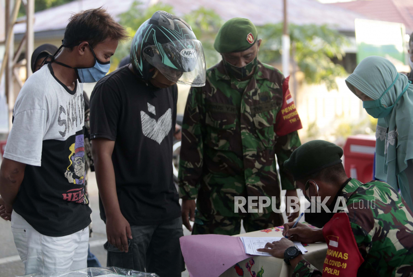 Anggota TNI dan petugas kesehatan mendata warga yang tidak mengenakan masker saat melintasi Kambungu Molotolo (kampung kuat) disiplin protokol kesehatan di Hutuo, Kabupaten Gorontalo, Gorontalo, Senin (8/6/2020). Polda Gorontalo bersama TNI dan Pemerintah Kabupaten Gorontalo membuat kawasan tersebut menjadi lokasi percontohan penerapan protokol kesehatan dalam kehidupan sehari-hari untuk mencegah penyebaran COVID-19