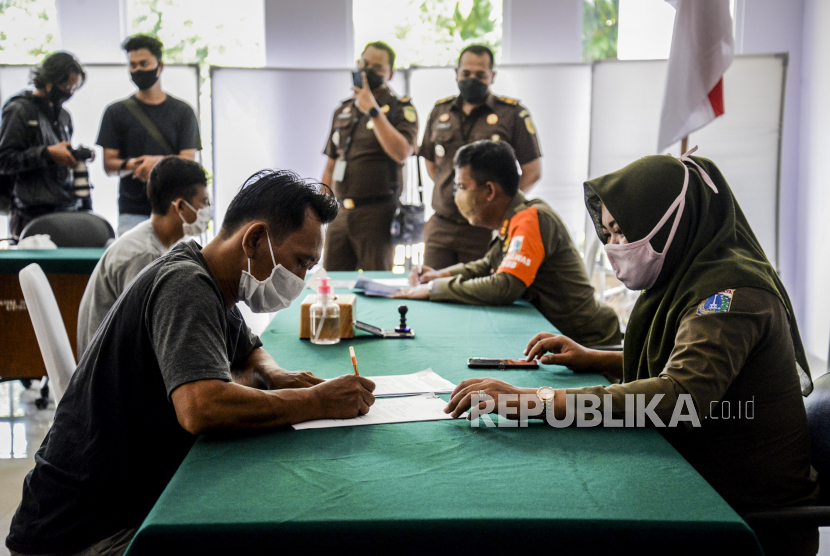 Petugas Satpol PP saat mendata pelanggar protokol kesehatan saat Operasi Yustisi Protokol Covid-19 di kawasan Jati Padang, Jakarta, Kamis (17/9).
