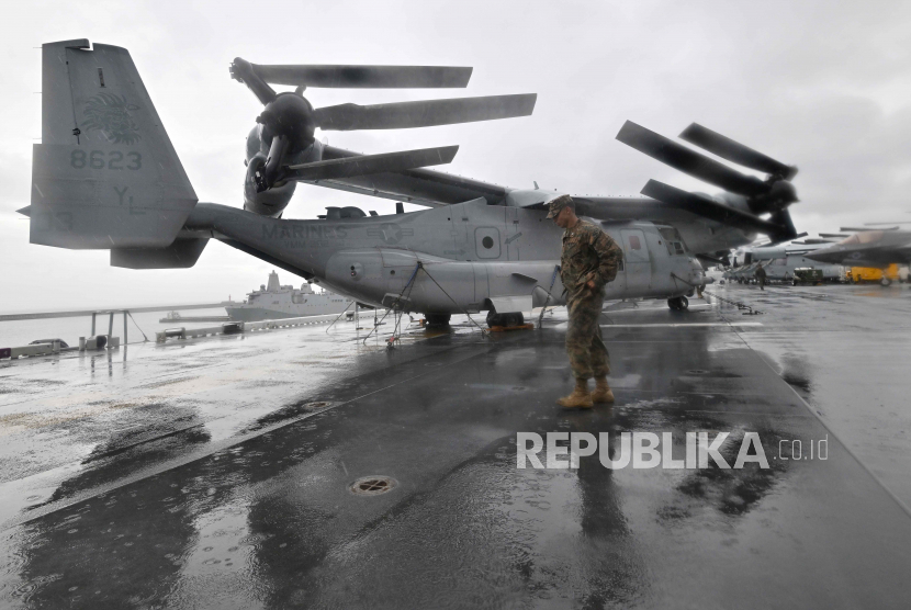  Seorang marinir AS berjalan melewati pesawat tiltrotor MV-22 Osprey AS.