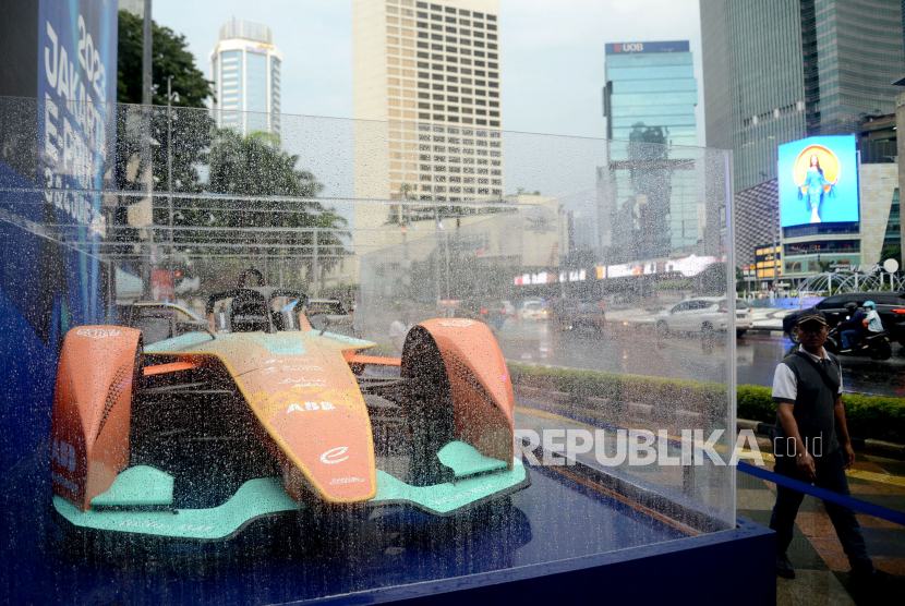 Warga melintas di samping replika Mobil Formula E di Bundaran HI, Jakarta, Ahad (26/3/2023). Replika Mobil Formula E tersebut dipajang sebagai promosi menjelang pelaksanaan balap formula E di Jakarta pada 3 dan 4 Juni 2023 mendatang. 