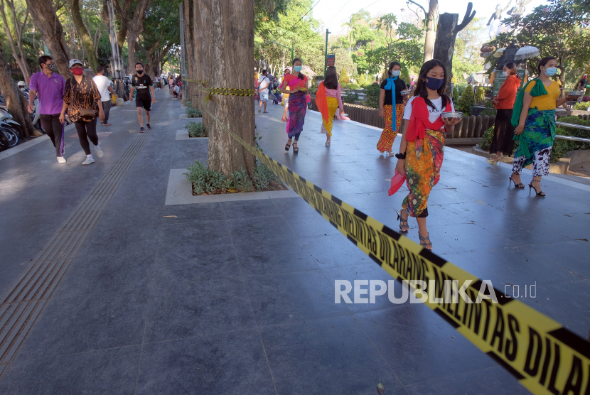 Warga beraktivitas di dekat garis larangan melintas di Lapangan Puputan Badung, Denpasar, Bali, Ahad (13/9/2020). Pemerintah Kota Denpasar kembali menutup sejumlah ruang publik yang ramai dikunjungi masyarakat menyusul melonjaknya kasus penularan COVID-19 di Bali. 