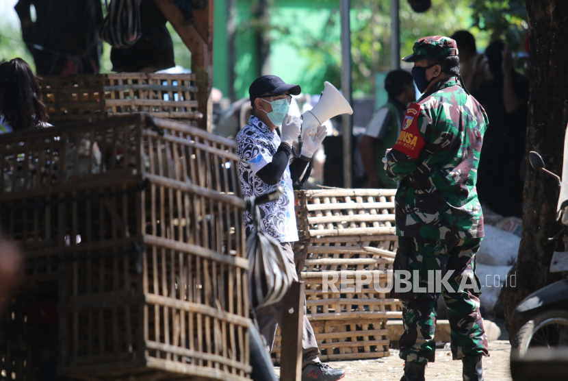 Petugas melakukan sosialisasi penggunaan masker sekaligus meminta pedagang untuk mengosongkan pasar Banjaran, di Kota Kediri, Jawa Timur, Ahad (10/5/2020). Pemerintah daerah setempat menutup pasar tradisional itu selama tiga hari pasca seorang pedagang dinyatakan positif COVID-19