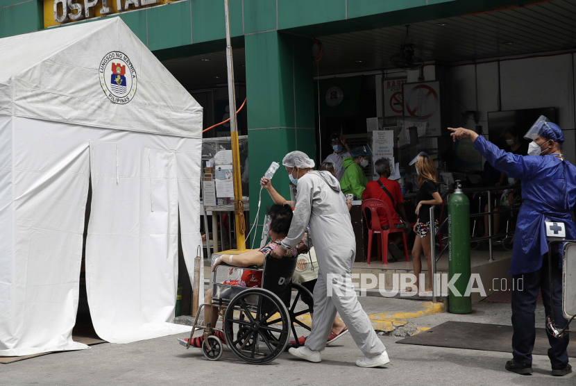Seorang petugas kesehatan yang mengenakan pakaian pelindung mendorong pasien Covid-19 ke tenda isolasi di luar rumah sakit di Manila, Filipina. Asia Tenggara mengalami rekor peningkatan kasus dan kematian akibat Covid-19. Ilustrasi.