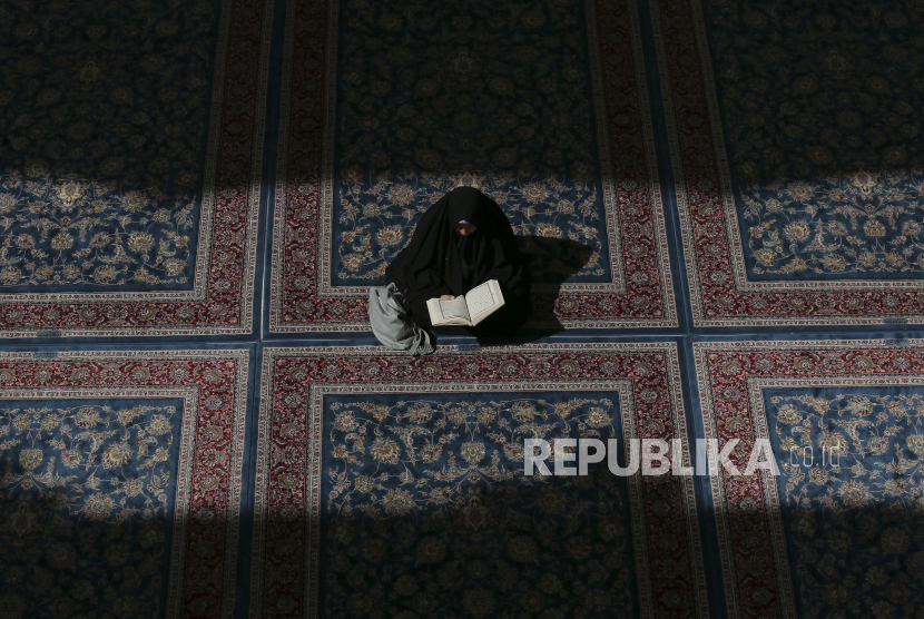 Seorang wanita berdoa dan membaca Alquran di tempat suci Imam Ali untuk menandai dimulainya bulan suci Ramadhan di Najaf, 160 kilometer (100 mil) selatan Baghdad, Irak, Ahad, 3 April 2022. Tersentuh Alquran, Perempuan Islandia Anti-Islam Ini Temukan Hidayah dan Jadi Mualaf