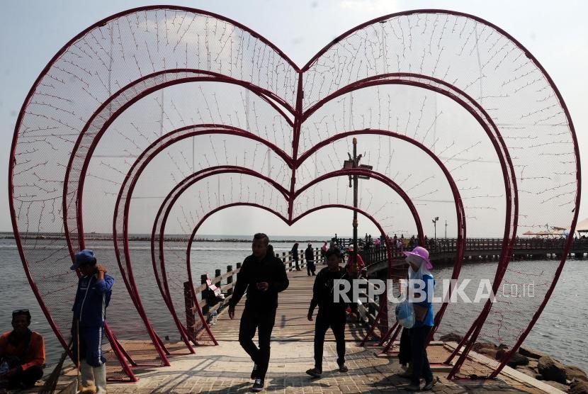 Sejumlah wisatawan berjalan di Jembatan Pantai Ancol, Jakarta, Ahad (17/6).