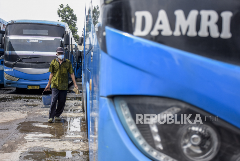 Pekerja berjalan di samping bus kota Damri Bandung yang berhenti operasi sementara di Pool Damri Kebon Kawung, Kota Bandung, Kamis (28/10). Damri Sediakan Angkutan Wisata Rute Stasiun Rangkasbitung-Pantai Sawarna