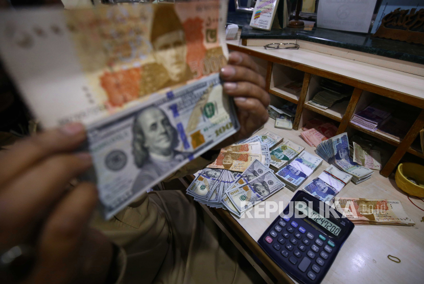 Petugas penukaran mata uang menyortir dolar AS dan rupee Pakistan di tokonya di Karachi, Pakistan, 12 Januari 2023. Dolar melemah usai Fed pertahankan suku bunga.