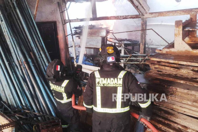 Personel UPT Pemadam Kebakaran berupaya memadamkan api yang membakar sebuah gudang tenda milik warga di Kelurahan Awirarangan, Kecamatan Kuningan, Kabupaten Kuningan, Jawa Barat, Ahad (11/6/2023).