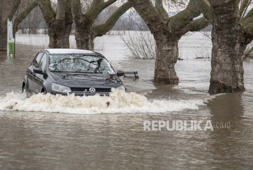  Seorang pengemudi mengemudikan mobilnya di atas jalan di Rhine yang telah banjir dan ditutup oleh air pasang di Ruedesheim, Jerman. Para ahli khawatir cuaca ekstrem menunjukkan iklim telah melewati ambang batas bahaya. 