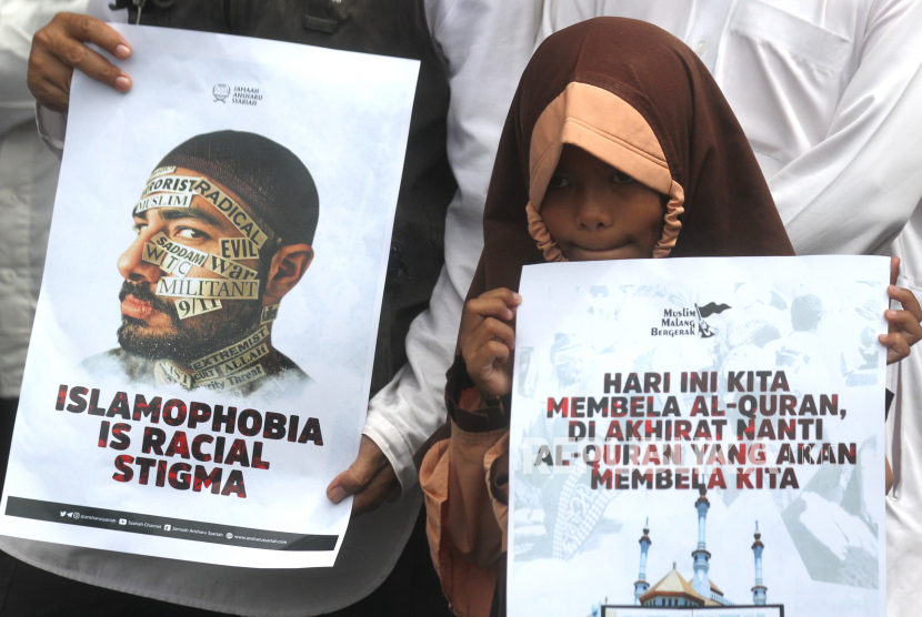Pengunjuk rasa yang tergabung dalam komunitas Muslim Malang Bergerak membawa poster Rasmus Paludan saat berunjuk rasa. 
