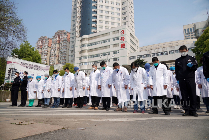 Pekerja medis menundukkan kepala mereka pada saat hari berkabung nasional untuk para korban virus corona di Wuhan, Provinsi Hubei, China 