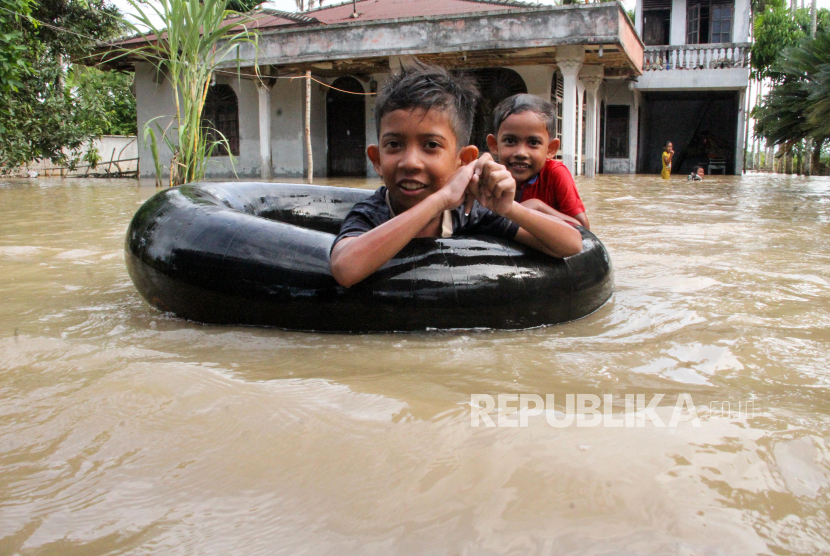 Sejumlah anak bermain dengan banjir yang merendam Desa Alue Thoe,  Matangkuli, Aceh Utara, Aceh, Senin (18/5/2020). Banjir yang disebabkan luapan sungai Pirak, Kreuto dan Krueng Haji setelah diguyur hujan dalam beberapa hari terakhir menyebabkan ribuan rumah warga di lima kecamatan di Aceh Utara terendam banjir