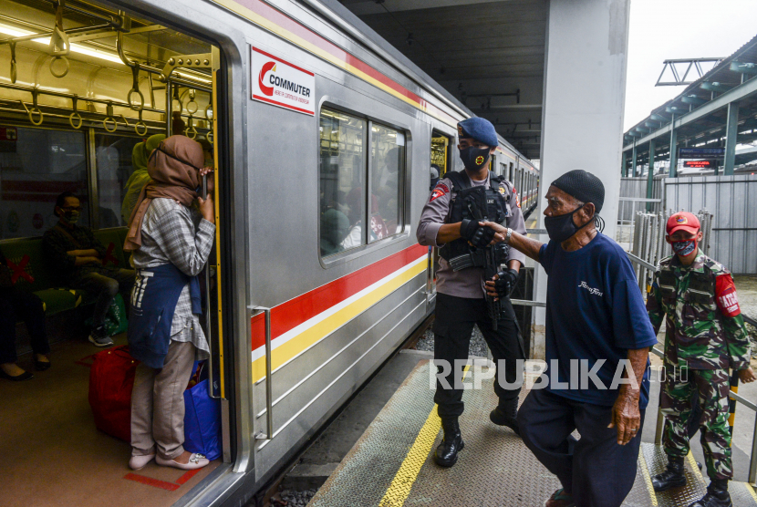 Anggota TNI dan Polri membantu lansia yang akan menaiki KRL di Stasiun Manggarai, Jakarta, Kamis (28/5). PT Kereta Commuter Indonesia menerapkan kedisiplinan protokol kesehatan di lingkungan KRL menjelang diberlakukannya tatanan normal baru