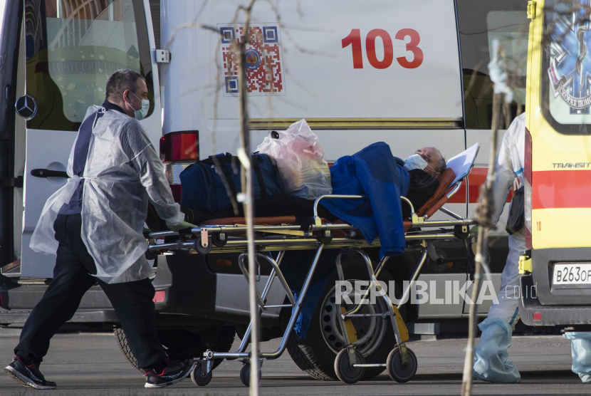 Para pekerja medis mengenakan alat pelindung membawa tandu seorang pasien yang dicurigai terinfeksi virus corona di sebuah rumah sakit di Kommunarka, Moskow, Rusia, Rabu (29/4). Pemerintah Rusia berencana melonggarkan lockdown.
