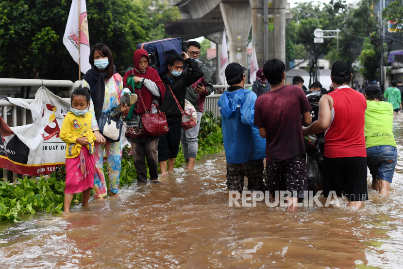 Warga melintasi banjir di Jalan Wolter Monginsidi, Kebayoran, Jakarta, Sabtu (20/2/2021). Intensitas hujan yang tinggi menyebabkan banjir di sejumlah wilayah Ibu Kota dan sebagian ruas jalan tidak dapat dilewati kendaraan. ANTARA FOTO/Wahyu Putro A/rwa.