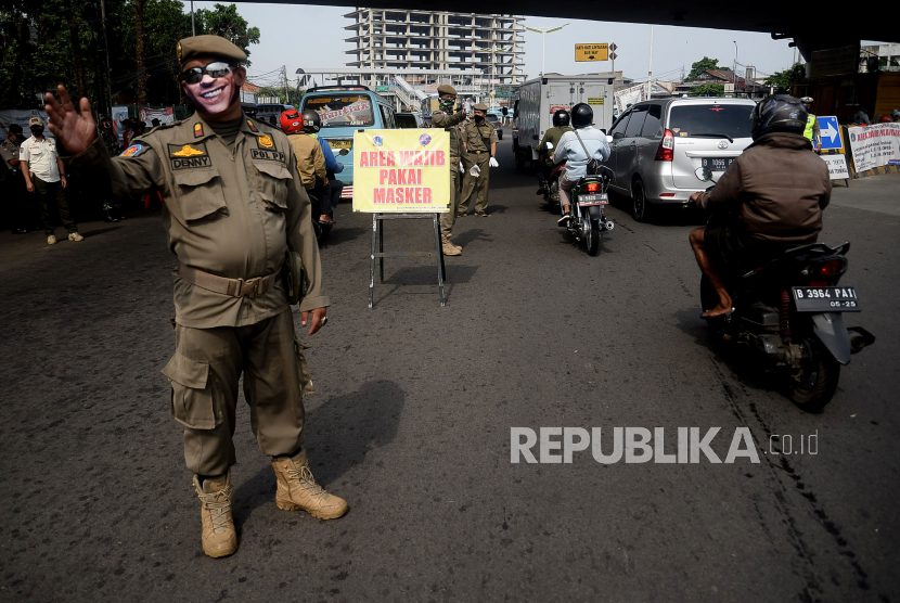 Petugas mengawasi warga yang tidak memakai masker di kawasan terminal Kampung Melayu, Jakarta, Jumat (5/6). Warga DKI Jakarta diwajibkan menggunakan masker ketika beraktivitas pada masa transisi Pembatasan Sosial Berskala Besar (PSBB)