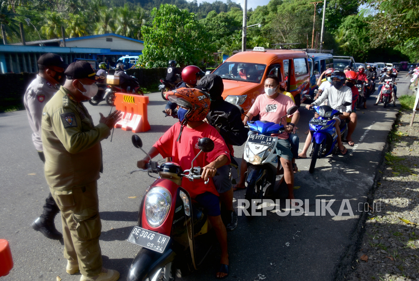 Sejumlah petugas dari Satpol PP dan Polisi memeriksa persyaratan perjalanan di pos pemeriksaan Pemberlakukan Pembatasan Kegiatan Masyarakat (PPKM) di Desa Suli perbatasan Kabupaten Maluku Tengah dengan Kota Ambon, Provinsi Maluku, Ahad (1/8/). Satgas Covid-19 Ambon mendirikan pos pemeriksaan di perbatasan guna memeriksa warga dari luar daerah yang akan masuk ke Ambon untuk mencegah penyebaran Covid-19. 