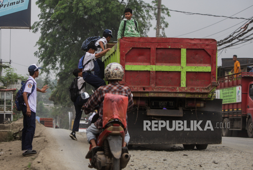 Pelajar menaiki truk yang melintas di Jalan Sudamanik, Kecamatan Parungpanjang, Kabupaten Bogor, Jawa Barat, Senin (20/11/2023). 