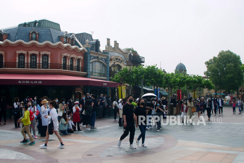 Pengunjung berjalan di taman bermain Disneyland saat dibuka kembali setelah penutupan imbas virus corona di Shanghai, China, Senin (11/5). Taman hiburan paling terkemuka di China dibuka kembali pada hari Senin untuk mampu mengontrol penyebaran virus corona dan untuk memulihkan bidang perekonomian