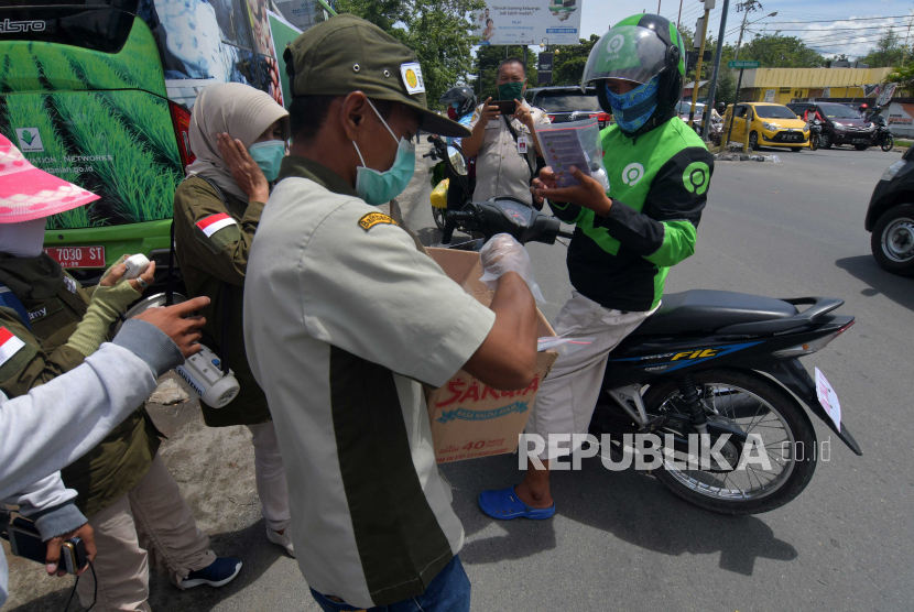 Petugas Balai Pengkajian Teknologi Pertanian (BPTP) Sulawesi Tengah membagikan paket pembersih tangan kepada pengemudi ojek daring yang melintas di Palu, Sulawesi Tengah, Selasa (7/4/2020). Pembagian pembersih tangan serta cairan disinfektan alami dari BPTP Sulawesi Tengah dalam program 
