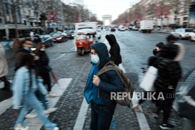 Seorang pria yang mengenakan masker untuk mencegah penyebaran COVID-19, melintasi jalan Champs Elysees, di Paris, Selasa, 28 Desember 2021. Pemerintah Prancis telah mengumumkan langkah-langkah baru COVID-19 dalam upaya untuk mengekang penyebaran dari virus. 