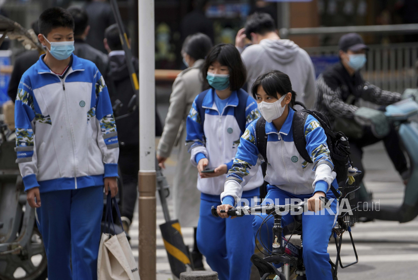 Siswa sekolah menengah yang mengenakan masker bertanya-tanya di sepanjang jalan Kamis, 28 April 2022, di Beijing. Beijing mengatakan akan mengizinkan Sekolah Dasar dan Sekolah Menengah Pertama untuk menggelar kelas tatap muka. 