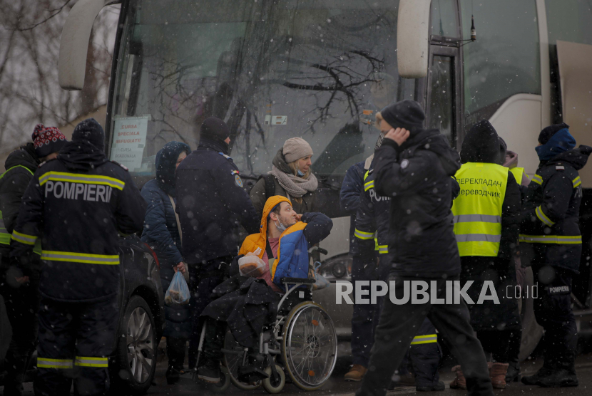 Seorang pengungsi pengguna kursi roda yang melarikan diri dari konflik dari negara tetangga Ukraina berbicara dengan petugas polisi di perbatasan Rumania-Ukraina, di Siret, Rumania, Kamis, 3 Maret 2022. 