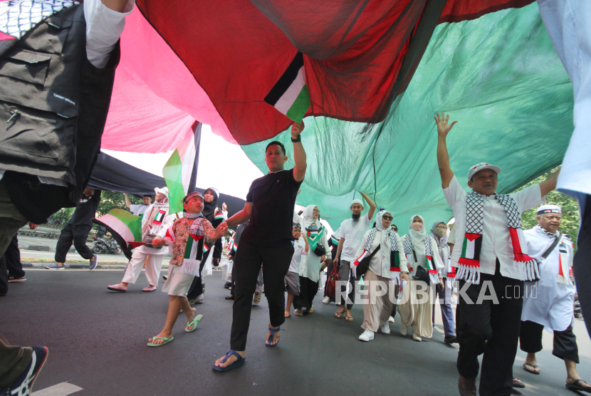 Peserta aksi membawa bendera Palestina raksasa saat aksi solidaritas untuk Palestina di depan Gedung Sate, Kota Bandung, Jawa Barat, Jumat (17/11/2023). 