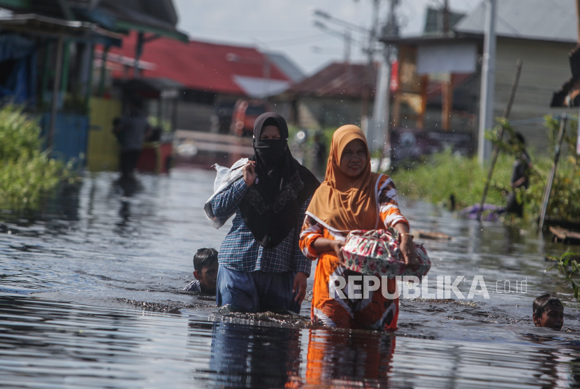 Warga melintas di permukiman sekitar rumahnya yang terendam banjir di Jalan Anoi Ujung, Palangkaraya, Kalimantan Tengah.