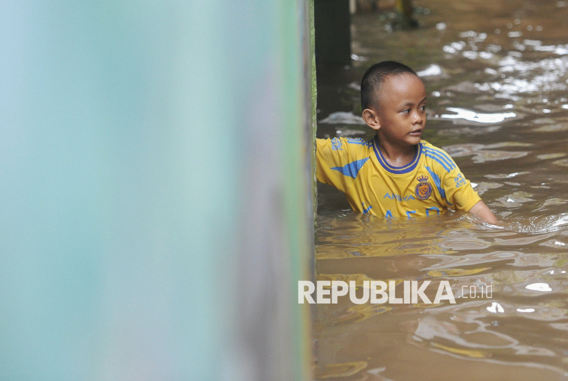 Seorang anak berjalan melintasi banjir yang melanda kawasan Kebon Pala, Kampung Melayu, Jakarta, Kamis (30/1/2025).