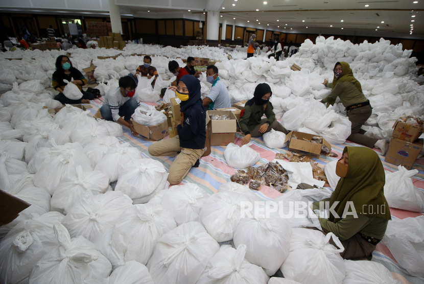 Relawan membungkus paket sembako bantuan dari berbagai perusahaan di Convention Hall, Surabaya, Jawa Timur, Ahad (26/4/2020). Bantuan sembako sebanyak 68