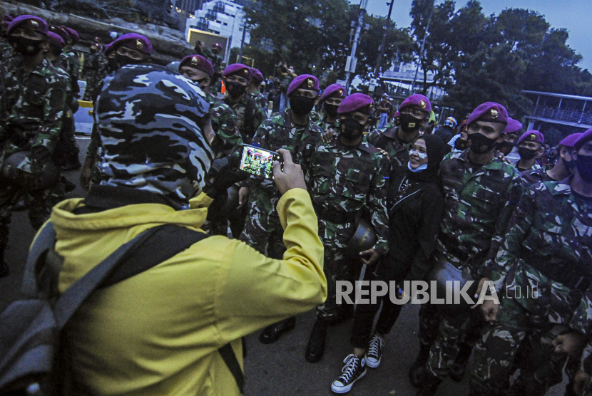 Seorang massa aksi berfoto dengan anggota TNI usai unjuk rasa di Jakarta, Selasa (20/10). Aksi tersebut berakhir tanpa kericuhan setelah anggota TNI membubarkan massa aksi. Republika/Putra M. Akbar