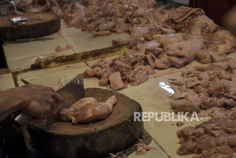 Pedagang memotong daging ayam di salah satu lapak di pasar.