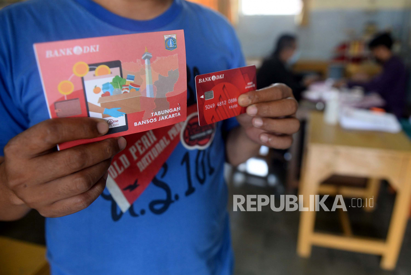 Warga menunjukan buku tabungan dan kartu debit usai mengambil Bantuan Sosial Tunai (BST) di SMPN 3, Jakarta, Selasa (26/1). Pencairan bansos Bantuan Sosial Tunai (BST) di Provinsi DKI Jakarta dilakukan secara bertahap mulai Januari-April 2021. Pencairan bansos di Jakarta yang dilakukan Bank DKI bersama Dinsos DKI Jakarta dibatasi hanya untuk 500 orang penerima per titik per hari demi menghindari penyebaran pandemi COVID-19.Prayogi/Republika 