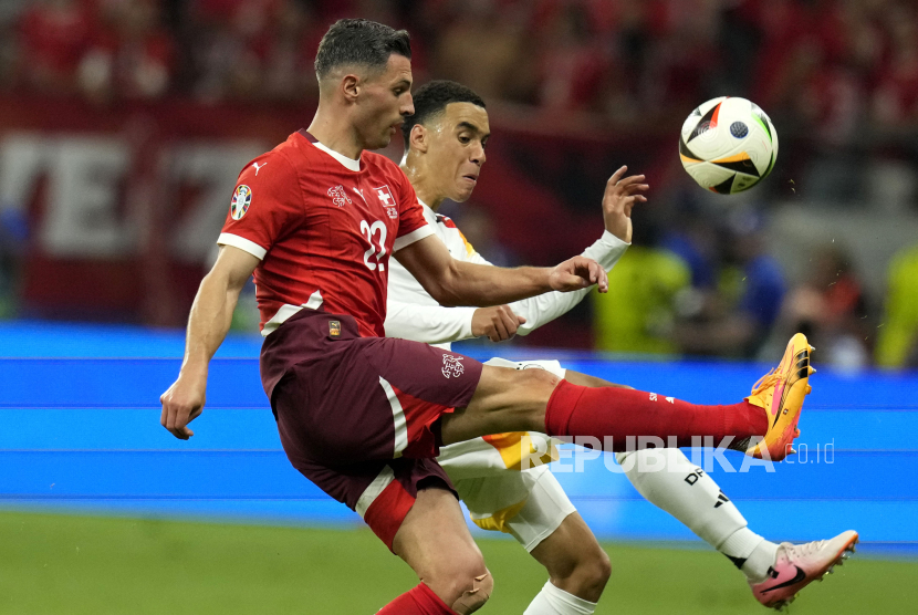 Pemain Jerman Jamal Musala berebut bola dengan pemain Swiss Fabian Schar dalam pertandingan Grup A Euro 2024 yang berakhir 1-1, di Frankfurt, Jerman, Ahad (23/6/2024).