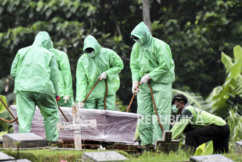 Petugas pemakaman menurunkan peti jenazah pasien Covid-19 di TPU Pondok Ranggon, Jakarta, Senin (30/3). (ilustrasi)