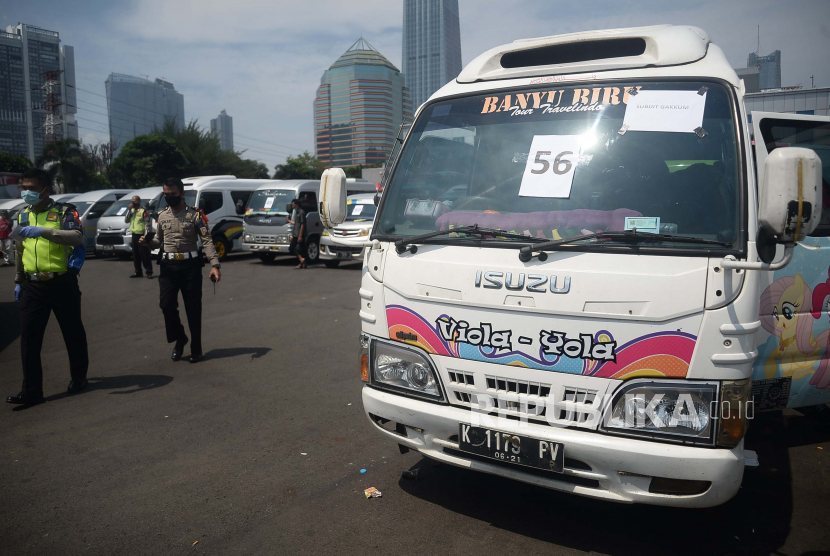 Seorang polisi melintas di depan mobil travel gelap yang terjaring dalam operasi khusus di titk penyekatan di Polda Metro Jaya, Jakarta, Senin (11/5). Dalam kurun waktu tiga hari operasi khusus tersebut, yakni mulai 8-10 Mei, Polda Metro Jaya mengamankan 202 kendaraan travel gelap yang mencoba mengangkut pemudik ke luar dari Jakarta