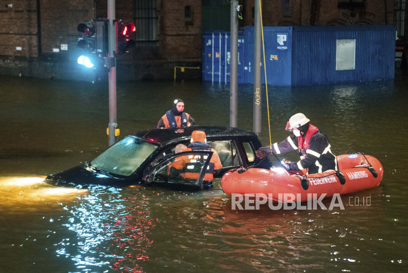 Petugas pemadam kebakaran menyelamatkan seorang pria dari mobilnya di jalan yang terendam banjir (ilustrasi).
