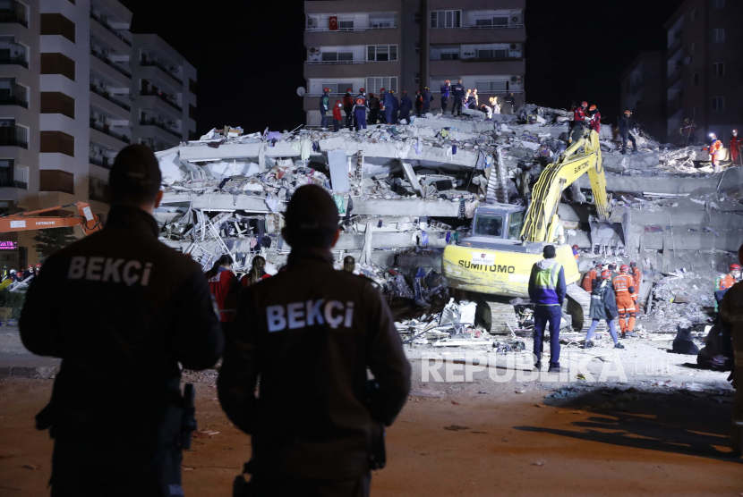  Anggota layanan keamanan mengawasi saat anggota layanan penyelamatan mencari korban di puing-puing bangunan yang runtuh di Izmir, Turki, Sabtu pagi, 31 Oktober 2020. Gempa bumi berkekuatan 5,9 skala richter (SR) melanda barat laut Turki pada Rabu dini hari. 