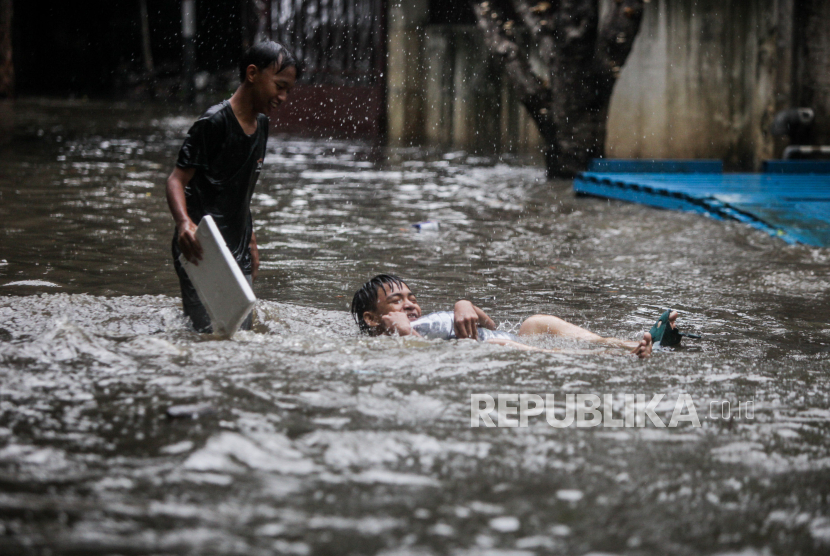 Anak-anak bermain air saat terjadi banjir di Pondok Karya, Mampang, Jakarta Selatan. Tim SAR masih mencari dua bocah yang terseret arus saat berenang di Kali Mampang.