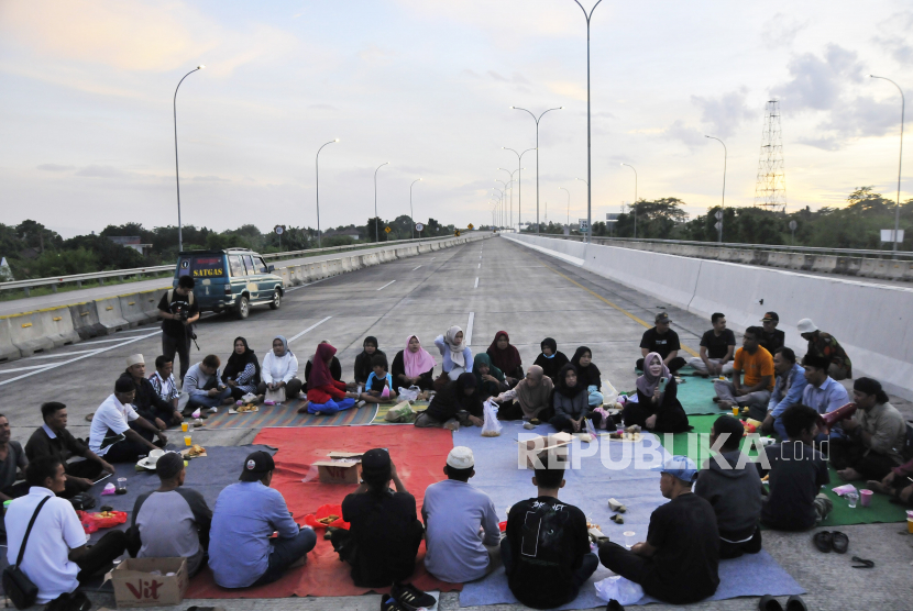 Sejumlah warga ahli waris melaksanakan buka puasa saat aksi penutupan Jalan Tol Jatikarya  di Bekasi, Jawa Barat, Senin (10/4/2023). Aksi penutupan jalan dari pukul 14.50 WIB tersebut menuntut pembayaran konsinyasi dari BPN (Badan Pertanahan Nasional) atas penggunaan tanah seluas 4,2 hektare untuk Tol Cimanggis-Cibitung di Jatikarya.  
