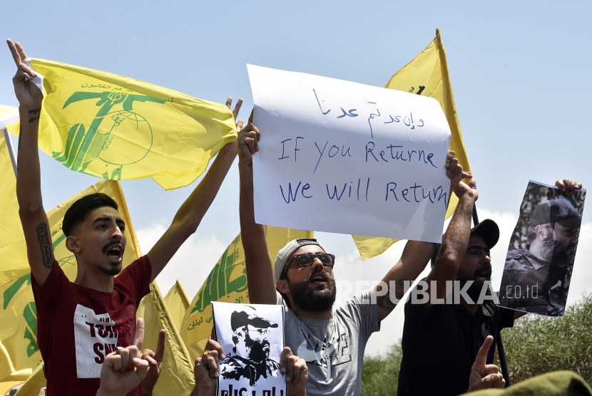  Pendukung Hizbullah membawa potret mendiang pemimpin Hizbullah Imad Mughnyeh, plakat dan bendera Hizbullah selama protes menentang kunjungan Komandan Komando Pusat Angkatan Darat AS, Kenneth Franklin McKenzie ke Lebanon di jalan raya bandara internasional Rafic Hariri di Beirut, Lebanon, 08 Juli 2020. 