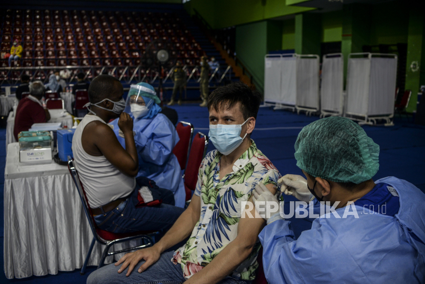 Tenaga kesehatan menyuntikan vaksin Covid-19 kepada pencari suaka di GOR Bulungan, Kebayoran Baru,  Jakarta, Kamis (7/10). Sebanyak 600 kuota dosis vaksin Sinopharm disiapkan untuk vaksinasi para pencari suaka dari 13 negara yang mengungsi di Jakarta. Republika/Putra M. Akbar