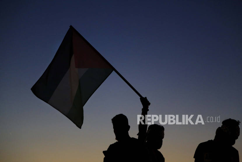 Warga mengibarkan bendera Palestina (ilustrasi).