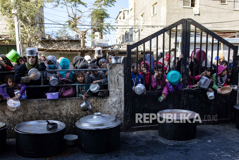 Warga Palestina yang mengungsi memegang panci dan ember kosong saat menunggu menerima bantuan makanan yang diberikan oleh kelompok pemuda Palestina di kamp pengungsi Rafah, Jalur Gaza Selatan, (25/1/2024).