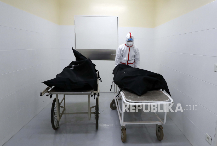 Seorang perawat mendorong korban COVID-19 dari kamar mayat kepada kerabat yang datang untuk mengambil jenazah di Rumah Sakit Nasional di Itagua, Paraguay, Senin, 7 September 2020.