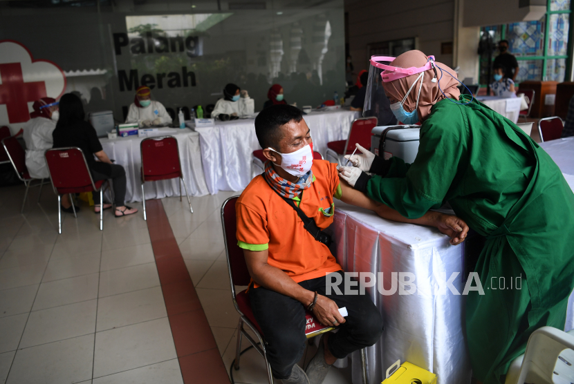 Petugas kesehatan menyuntikan vaksin COVID-19 kepada pedagang di Blok A Pasar Tanah Abang Jakarta, Kamis (25/2/2021). Kementerian Kesehatan memperpanjang periode vaksinasi COVID-19 pedagang di Pasar Tanah Abang hingga 2 Maret 2021 karena masih tingginya animo pedagang yang ingin divaksin mencapai 21.250 orang. 