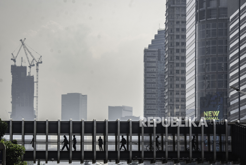 Warga berjalan di jembatan penyeberangan orang dengan latar belakang gedung perkantoran di Jakarta, Sabtu (26/9/2020). Realisasi penyerapan angagran Pemulihan Ekonomi Nasional (PEN) telah mencapai 30,9 persen atau Rp.254 triliun hingga minggu keempat September 2020 dari total anggaran Rp.695,2 triliun. 